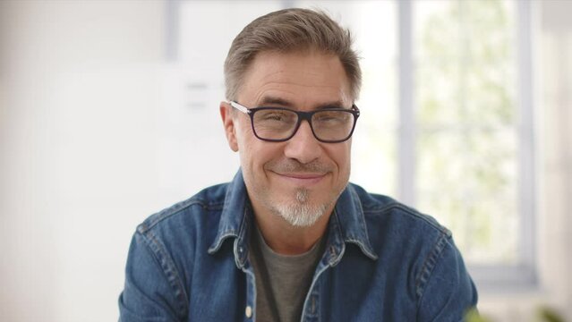 Portrait of happy mid-adult man wearing glasses and casual shirt, smiling. Mature age, middle age, mid adult man at home. Copy space.