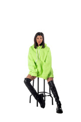 Attractive woman of Latin appearance wears a green hooded hoodie on a white background. The girl looks sexy and happy. The elegant brunette is wearing a dark sweatshirt. All-season clothing