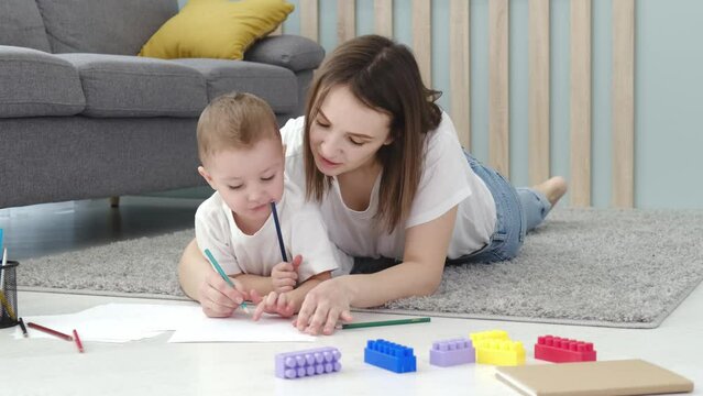 Happy little child boy hand drawing pictures with mom