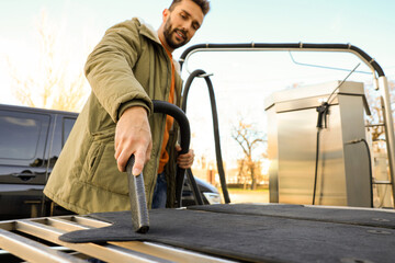Man cleaning auto carpets with vacuum cleaner at self-service car wash, low angle view