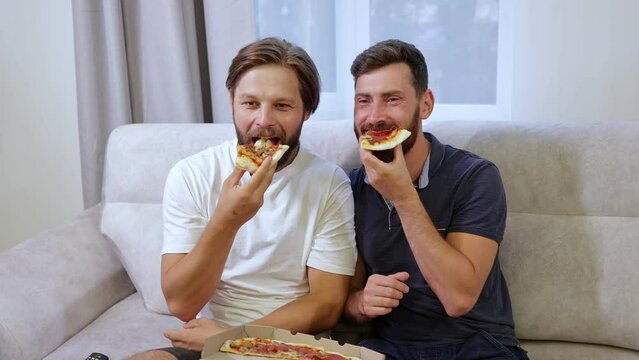 Cheerful Gay Couple Eating Pizza At Home. Spend Free Time In A Place