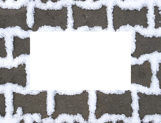 Blank white frame on dark grey footpath paving stones with white snow in gaps between. Stones...