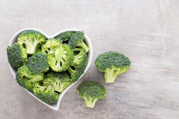 Fresh broccoli in a heart shaped bowl on a wooden background.