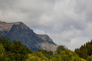 Obraz premium Mountains with stone, trees and pines in the Andes Mountains in Patagonia, Argentina. Sky with clouds.