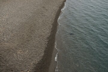 View of the famous black beach of Kamari without tourists in Santorini Greece