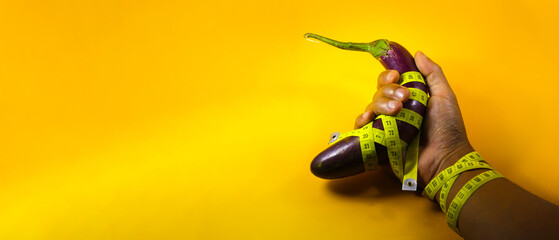 Close-up view of Purple eggplant on hand with copy space wrapped with yellow measuring tape...
