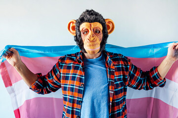 Man in monkey mask holding transgender flag.