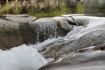 splashes of water on stones in a small waterfall, rapids of a mountain river with splashes