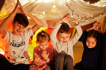 Playing kids in tent at night home. Hygge mood.