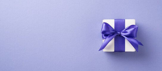 Top view photo of woman's day composition white giftbox with violet bow on isolated pastel purple background with empty space