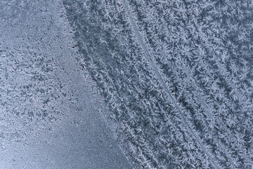 Frozen pattern of hoarfrost and frostwork structure on car windshield glass. Color texture photo for background. 