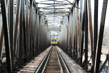 Stalowy most kolejowy nad rzeką w europie z pociągiem. - obrazy, fototapety, plakaty
