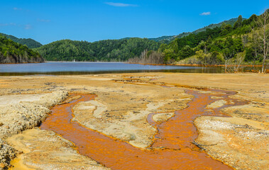 Mountain lake landscape - liquid residues from a gold mine discharged into a lake, pollution