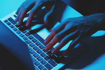 A man Using a laptop computer under blue light