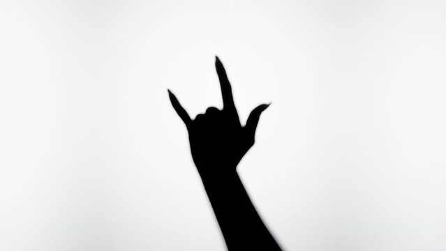 Woman showing rock and roll gesture with fingers isolated on white background. Female person making shadow silhouette with hand close-up.