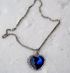 Close-up of the Heart of The Ocean necklace on snow. Titanic necklace. Blue diamond in a heart...