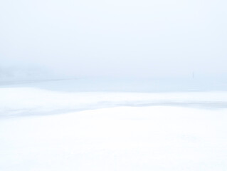 Fototapeta na wymiar Minimalist winter seascape of the frozen ocean and snowy sky. Soft Zen-like Asian painting style landscape with space for texts and design.