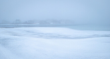 Minimalist winter seascape of the frozen snow-covered coastal beach on Cape Cod. Calm zen-like Asian painting style soft image with space for texts and design.