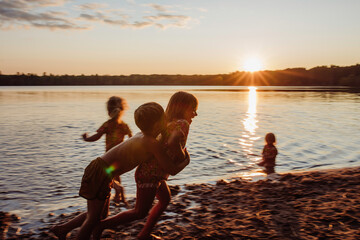 Kids at the beach playing sunset sunrise - obrazy, fototapety, plakaty