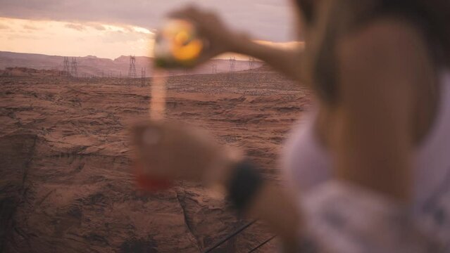 Two female friends drinking beer or wine and having fun outdoors in Arizona desert. Adventure, youth, love and friendship concept.