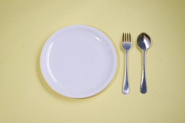 empty plate with cutlery on yellow background