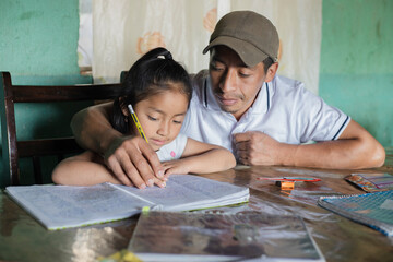 Hispanic dad helping his little daughter do her homework - Teacher teaching little girl to read and write - Mayan family at home