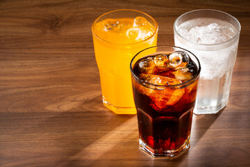 Glasses of soda flavors orange, lemon and coke.