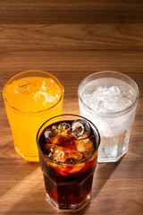Glasses of soda flavors orange, lemon and coke.