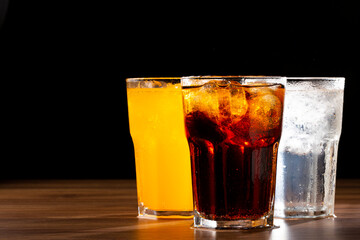 Glasses of soda flavors orange, lemon and coke.