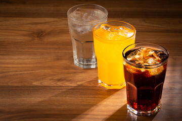 Glasses of soda flavors orange, lemon and coke.
