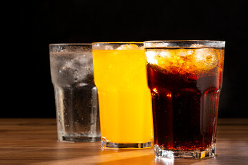 Glasses of soda flavors orange, lemon and coke.