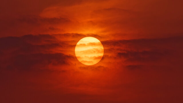 Fototapeta Close up view of sunset sun behind clouds like fire ball, telephoto lens shot.