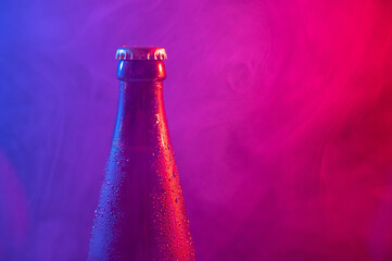 Glass bottle of beer in blue pink mist