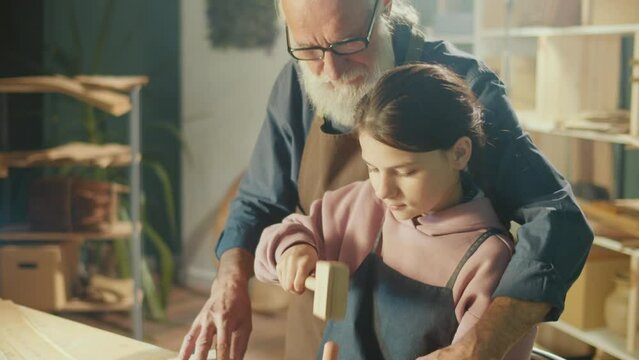 Grandfather Carpenter with Granddaughter Work with Wood to Create Items or Furniture Using Carpentry Tools. Training in Craft Skills in Home Workshop. Communication of Generations. Handicraft, Hobby.