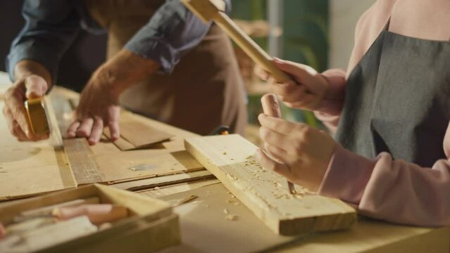 Close-up of Male Hands of Carpenter and Apprentice Doing Woodcarving. Making an Ornament on Wood Using a Chisel and a Hammer in a Workshop. Handicraft, Garage Hobby, Craft Skills Training.