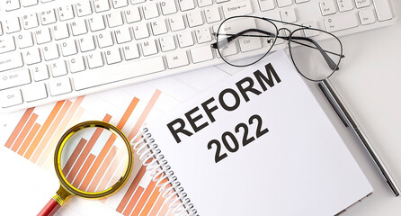 REFORM 2022 text written on a notebook with keyboard, chart,and glasses
