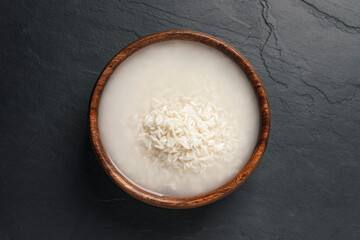 Rice soaked in water on black table, top view