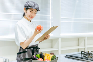 食品をチェックする女性（トマト・笑顔）
