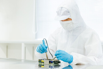 クリーンルームでハンダ付けする男性
