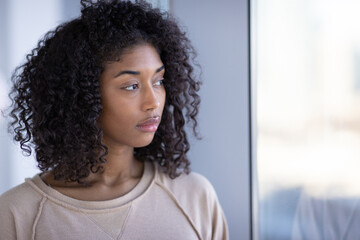 Young black woman at home sad depressed serious face portrait standing by a window
