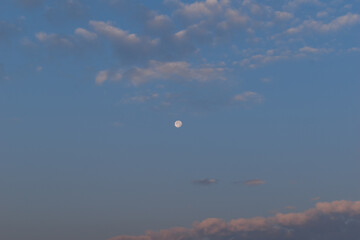 Full moon in beautiful blue cloudy sky in early morning