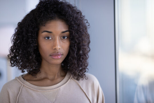 Young Black Woman At Home Sad Depressed Serious Face Portrait Standing By A Window