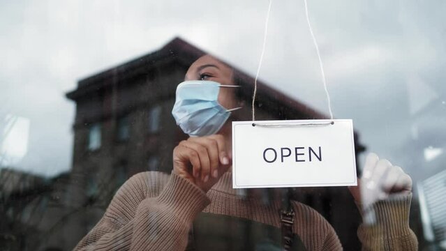 cafe or restaurants and business reopen after coronavirus quarantine is over. woman with face mask turning a sign on a door shop. small business after covid lockdown. small business open sign.