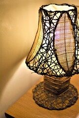 A bedside wicker lamp made of native rattan warmly lights a bedroom