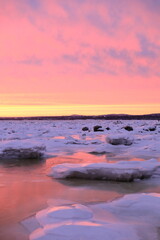 sunset over the sea with ice and snow winter