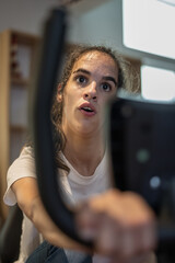 Obraz premium young physically disabled woman doing a stationary bike indoors