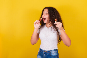 Afro brazilian, latin american girl with curly hair smiling, eating cheese and guava skewers,...