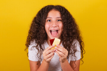 Afro-Brazilian, latin-american girl with curly hair smiling, holding skewers of cheese and guava,...