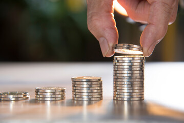 hand putting coins on coin stack