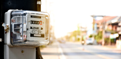 Electricity meters for household users are mounted on high-voltage poles by the side of the road.